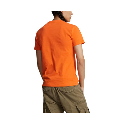 Retro modello con T-shirt in tinta unita arancione con cavallino sul petto in contrasto